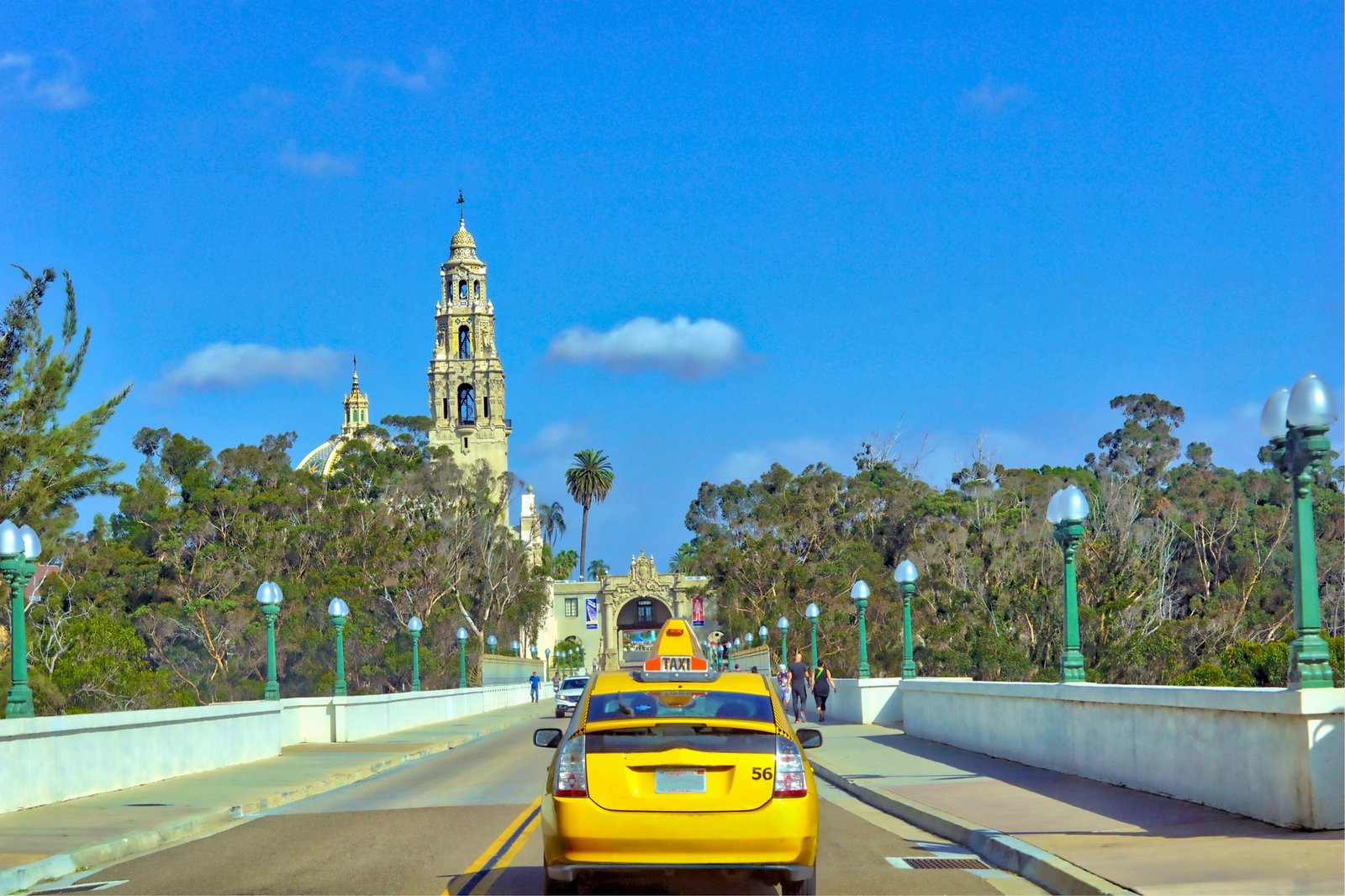 Yellow taxi driving over the iconic, 1915 Cabrillo Bridge, in San Diego California