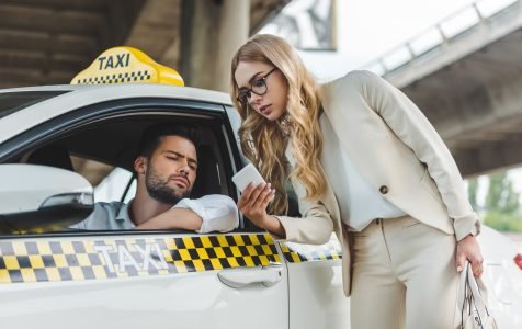 stylish blonde woman showing smartphone to the taxi driver
